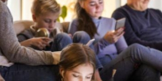 Photo d'une famille dans un salon, les uns lisant, les autres étant plongés dans des écrans