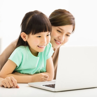 Une jeune femme avec une petite fille en âge d'apprendre à lire devant un ordinateur