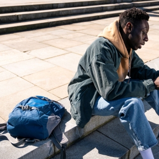 homme assis sur des marches dehors avec son téléphone à la main