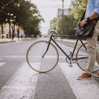 Jeune homme tenant son vélo pour traverser un passage piétons dans la rue